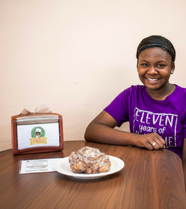 Smiling customer at Laila’s Place in Newberry, SC with a fresh blueberry fritter on the table.